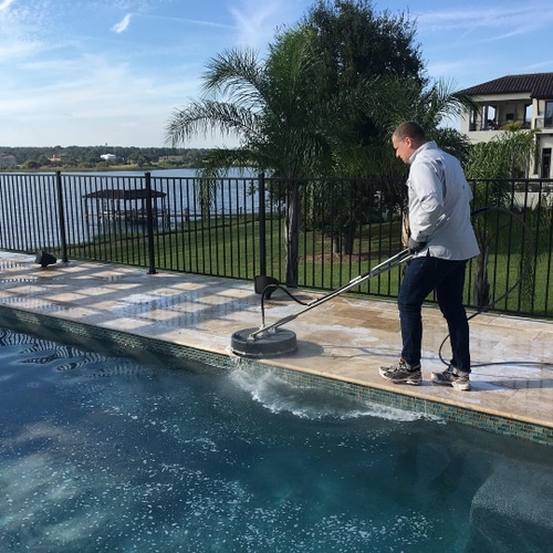 Cleaning a pool enclosure by the water